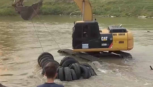 No primeiro dia de limpeza do rio Acre, retroescavadeira do Deracre retira imensa quantidade de pneus do manancial