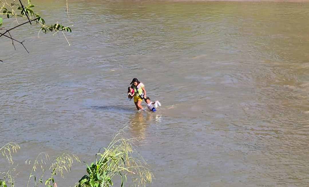 Mãe atravessa com o filho a pé o Rio Amônia, no interior do Acre, e cena revela cenário da seca extrema