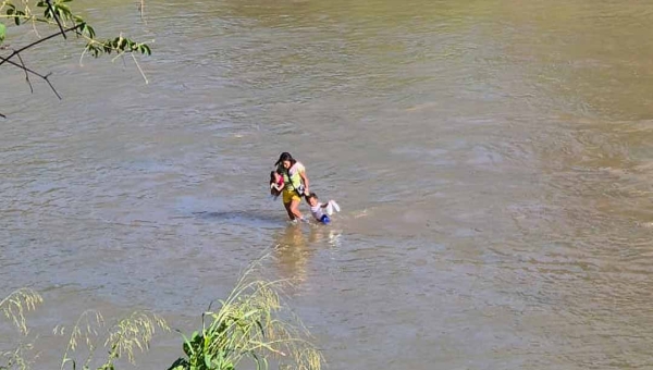 Mãe atravessa com o filho a pé o Rio Amônia, no interior do Acre, e cena revela cenário da seca extrema